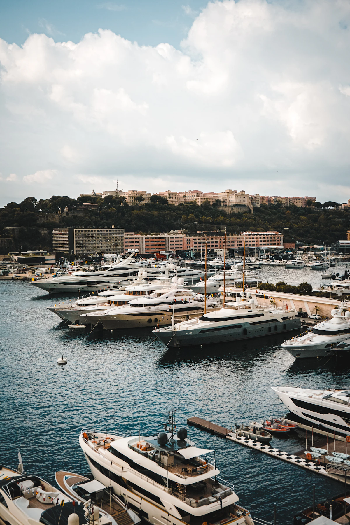 Superyachts moored in Monaco's harbour beneath the hillside city