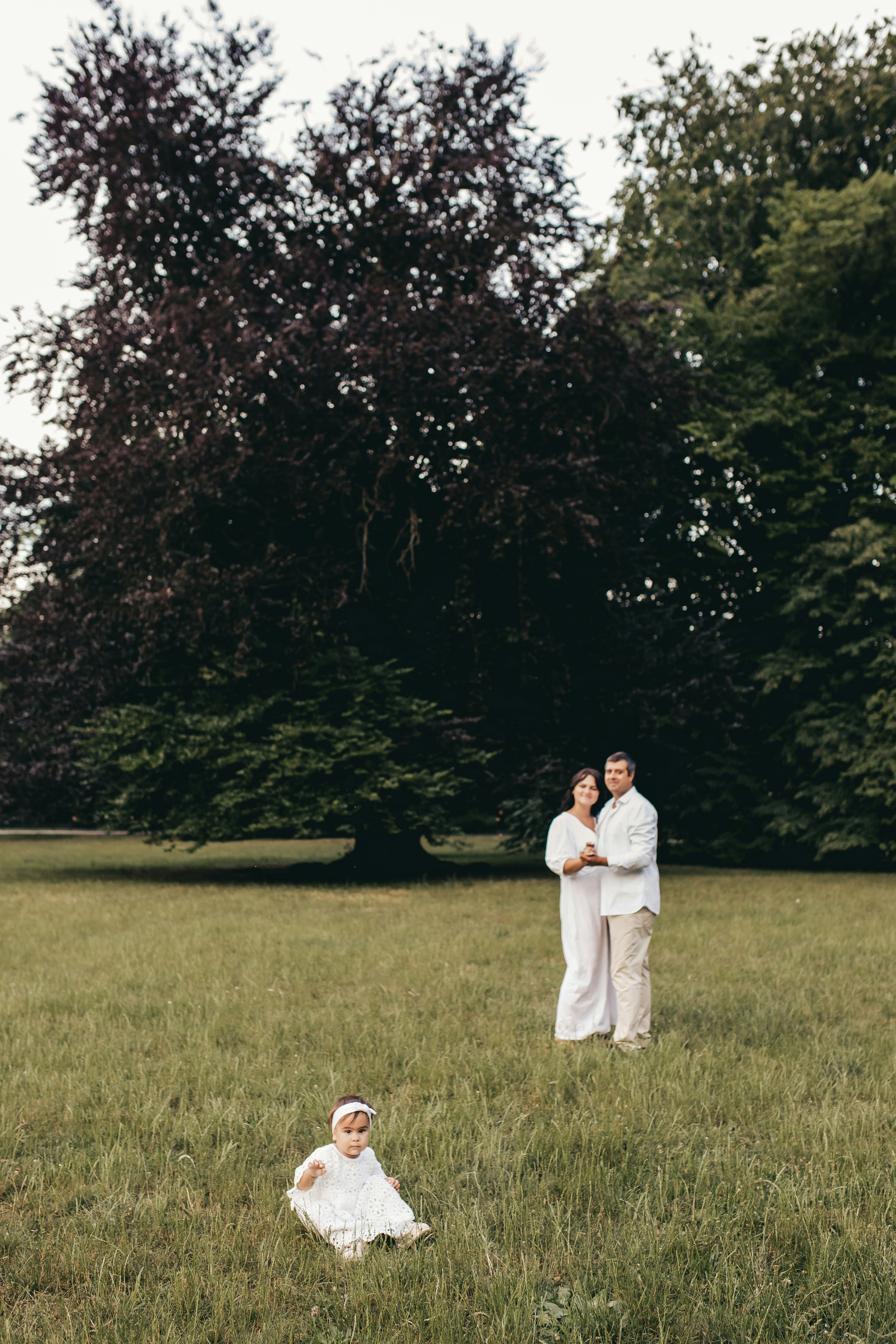 a man and woman standing in a field with a baby