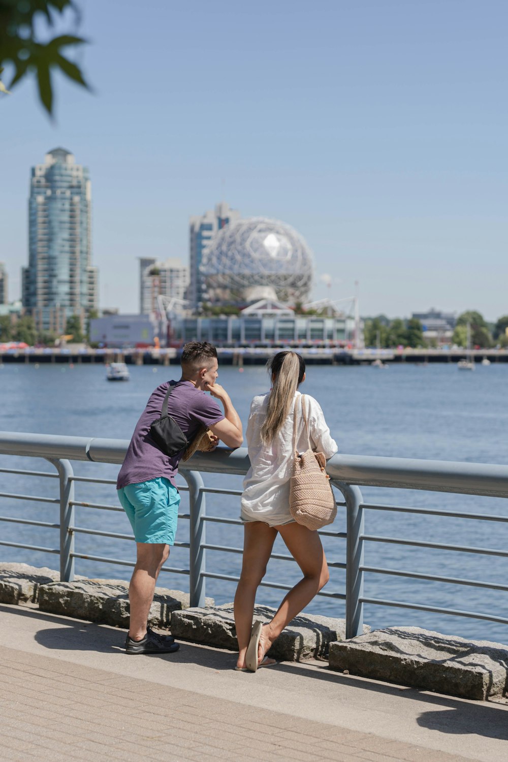 a man and woman kissing on a bridge over water