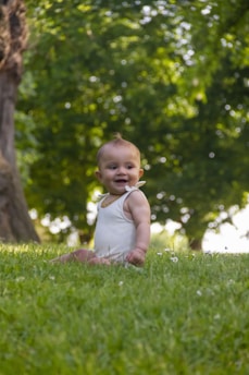 Toddler in a breathable cotton romper sitting outdoors under the sun.