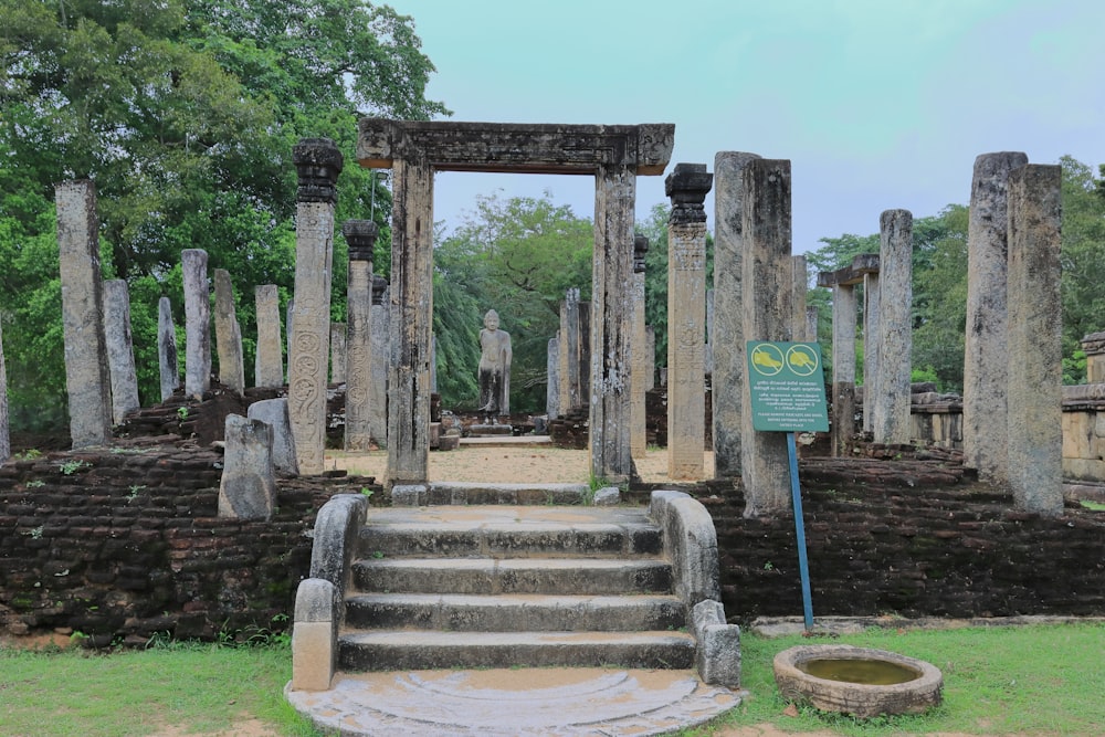 a stone structure with pillars and a statue in the middle