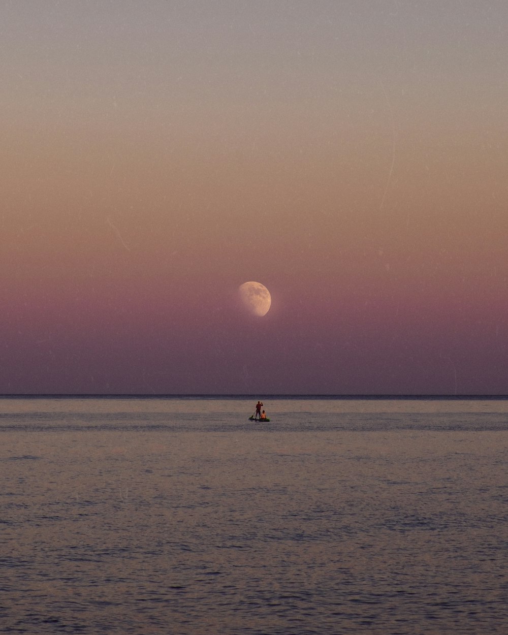 a person on a surfboard in the water with the moon in the background