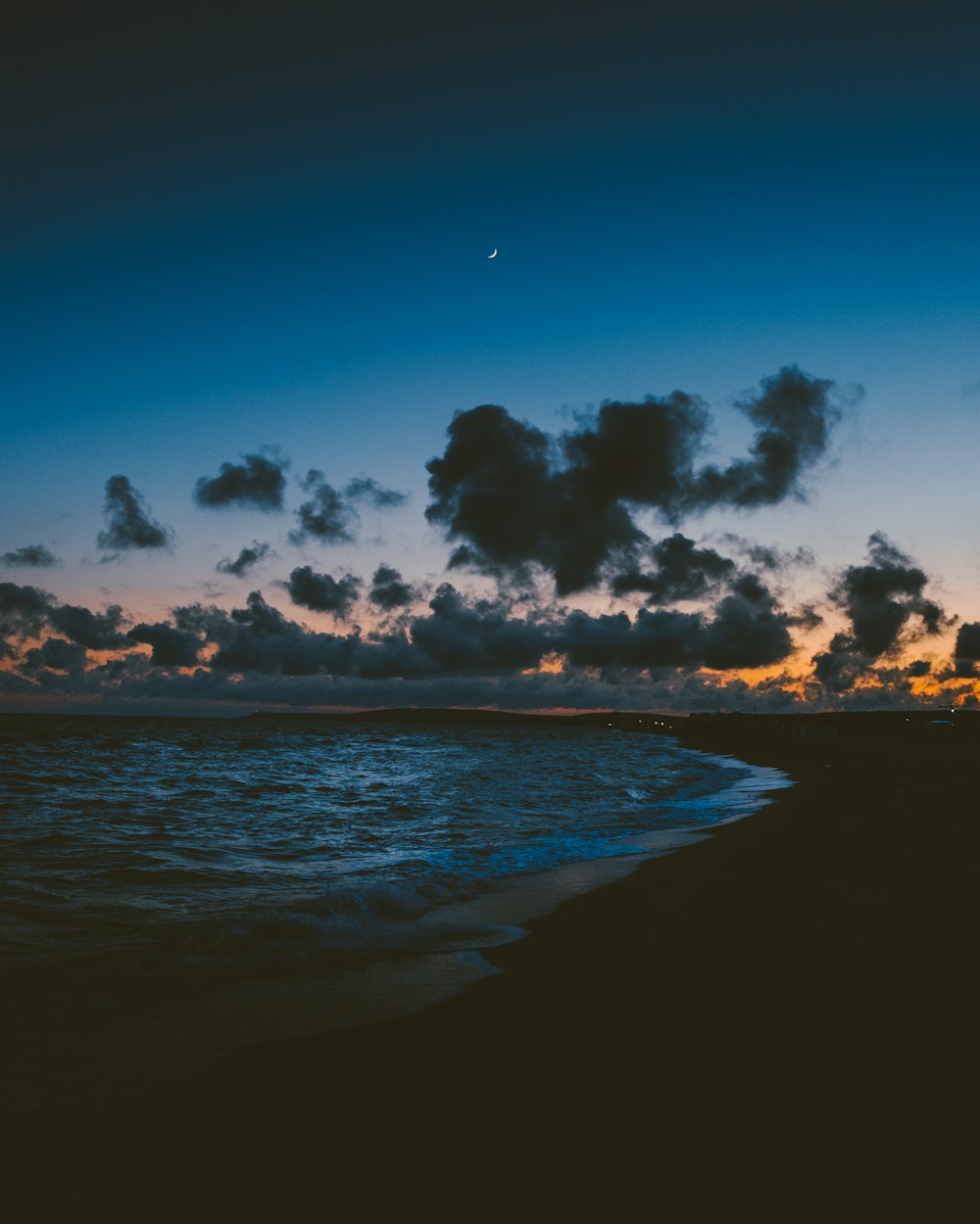 a beach with a body of water and a cloudy sky