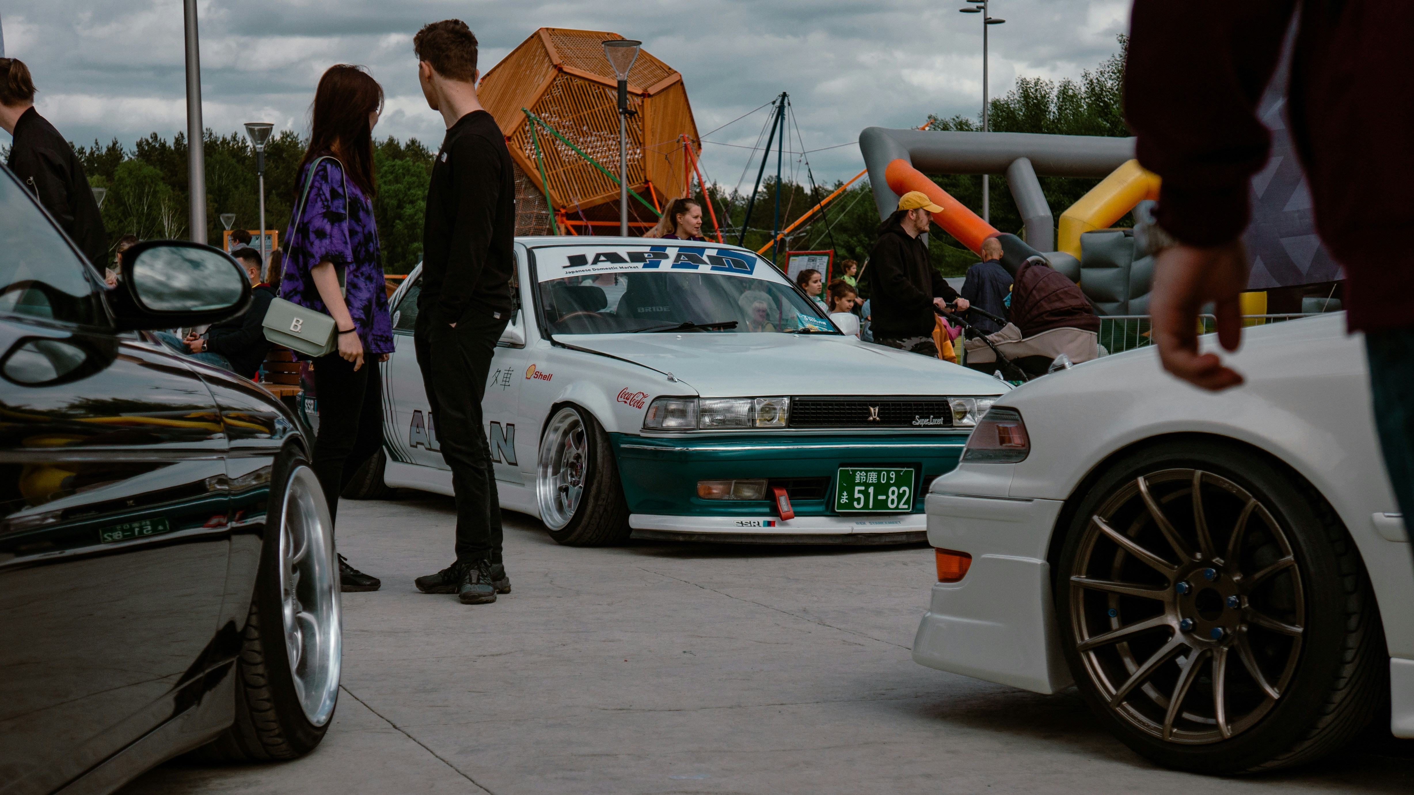 Group of car enthusiasts gathered around a modified sports car at a car meet event