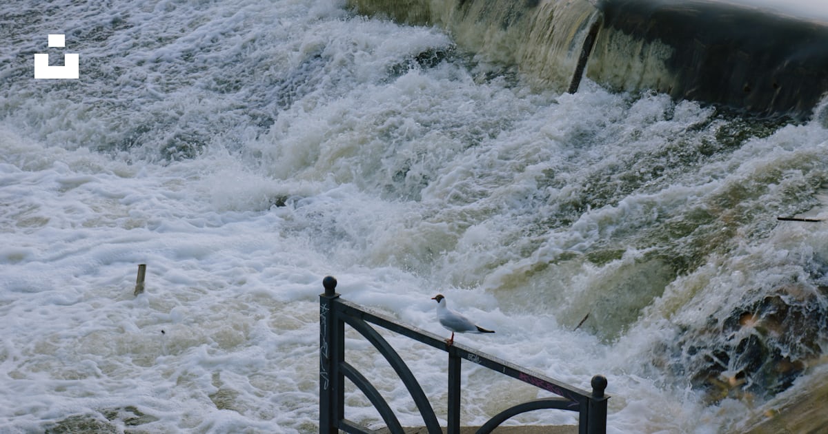 A river with a railing and a railing with a large waterfall photo ...
