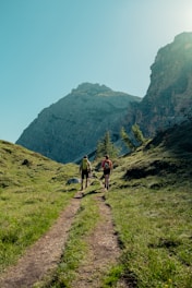 two people walking on a trail in a mountainous region