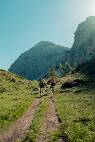 two people walking on a trail in a mountainous region