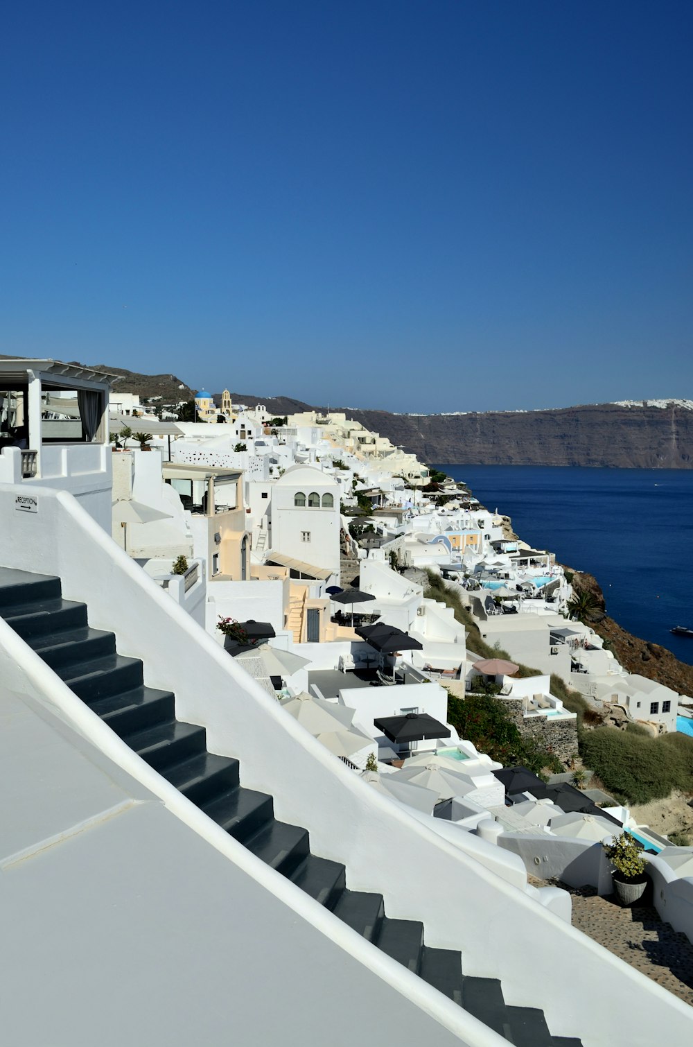 a white building with a pool and a beach with houses and trees