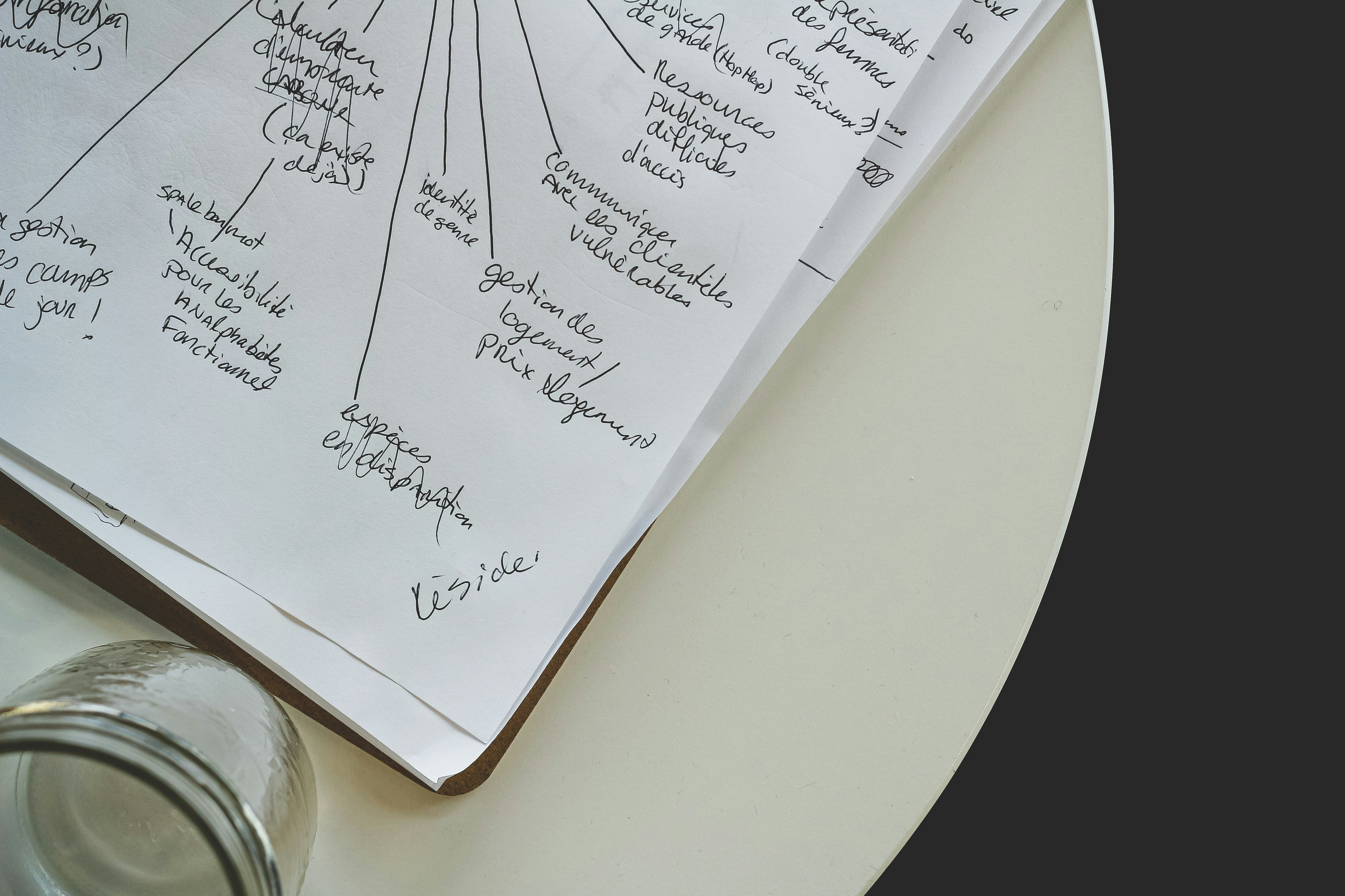 A woman sitting at a clean kitchen table with a laptop and a notepad, organizing her weekly family schedule and meals.