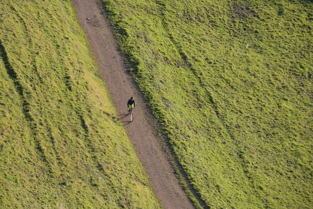 a person riding a bicycle on a dirt road in a field