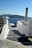 Gentle waves lapping white stone steps leading to a sunlit Greek villa, embodying tranquility.
