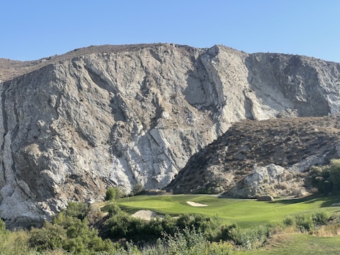 A dramatic volcanic mountain backdrop framing a pristine golf green in St. Lucia.
