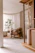 A cozy, sunlit living room corner featuring a minimalist wooden chair and a sculptural lamp from Cano Rolón Estudio.