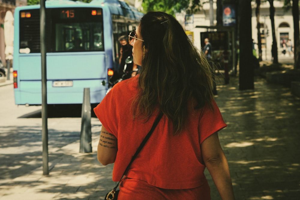 a person with a tattoo on the back looking at a bus