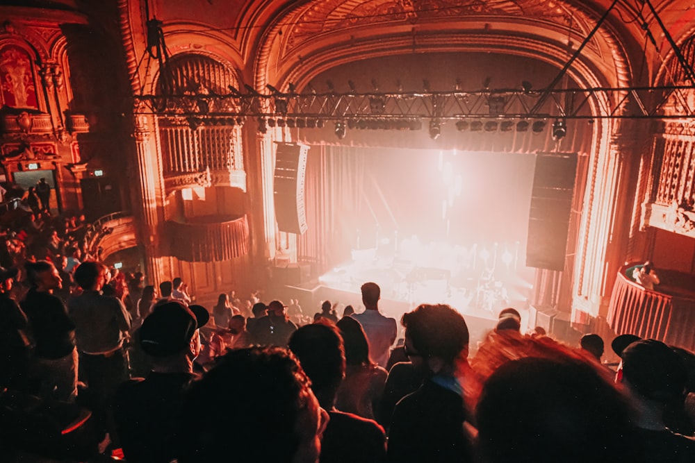 a group of people in a room with a stage and a large screen