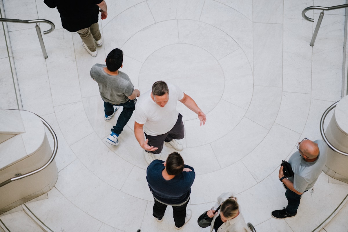 Overhead view of people moving across a circular marble floor, a collective process in motion