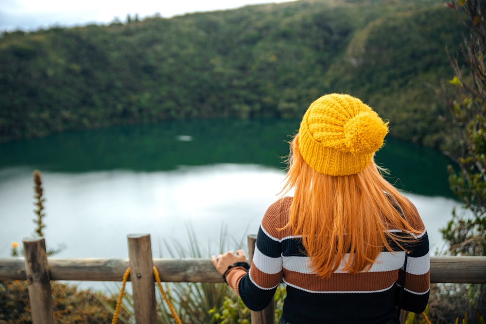 a person with a yellow hat looking at a body of water