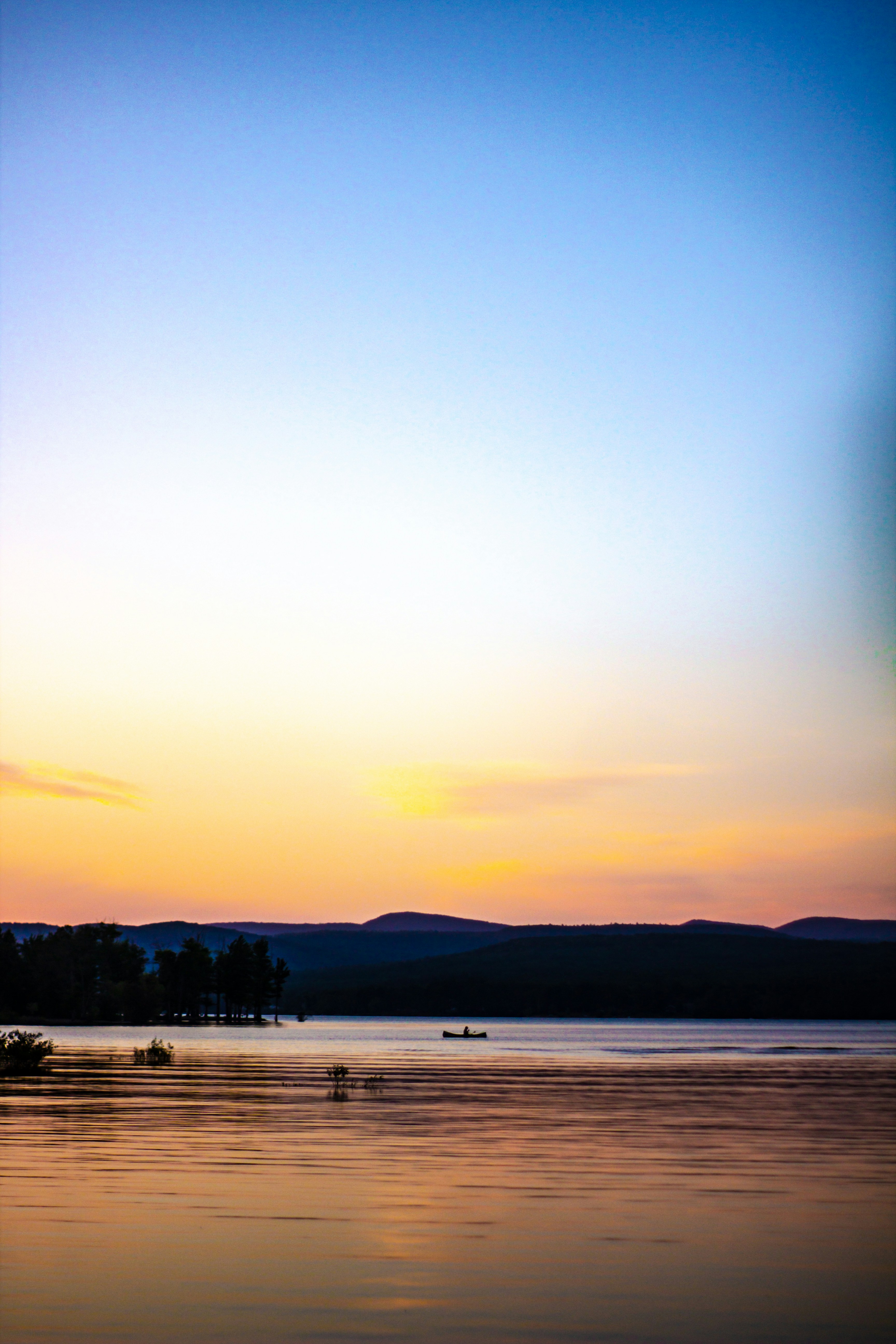 a beach with a boat in the water and mountains in the background