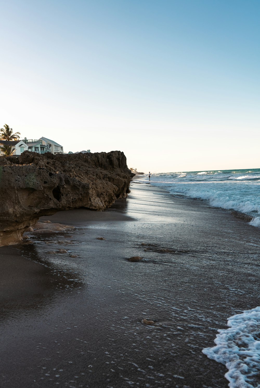 a rocky beach with a house on the shore