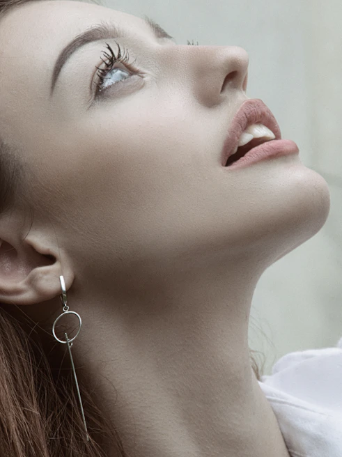 Model wearing minimalist sterling silver earrings with a gentle smile in natural light