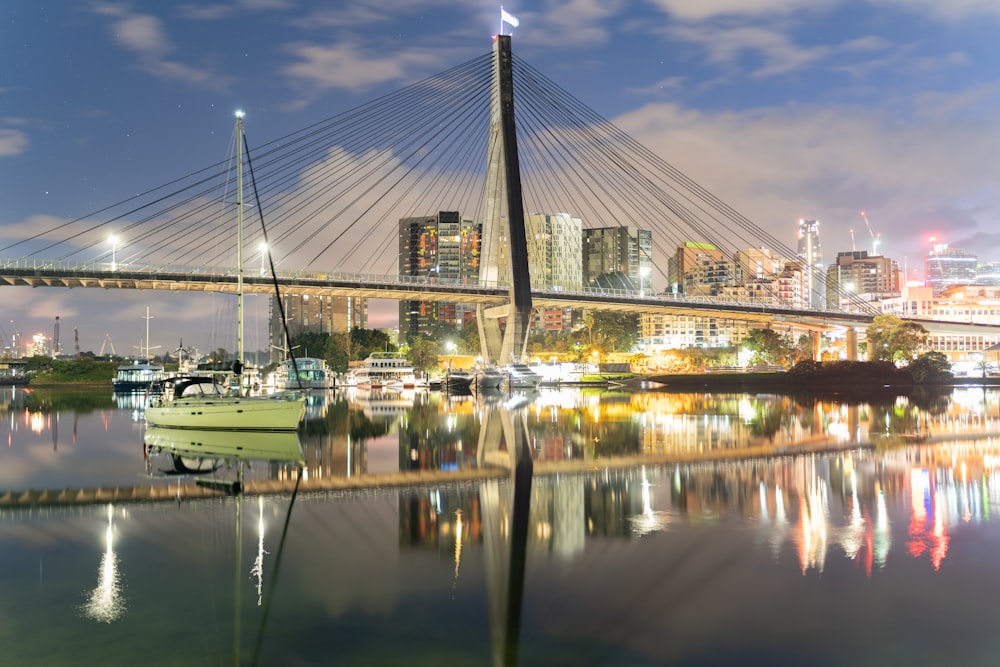 a bridge over water with boats on it and a city in the background