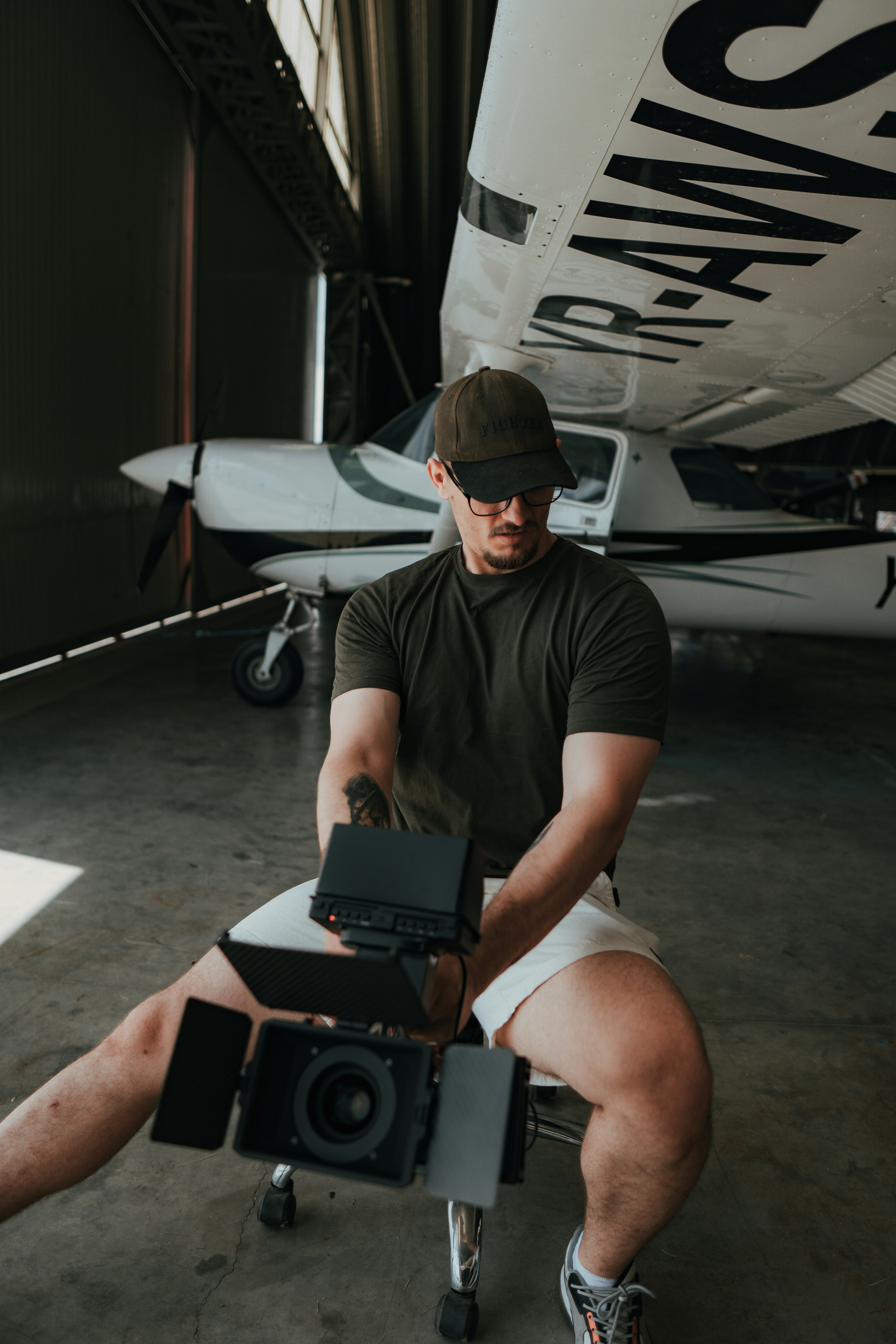 a man in a hat holding a laptop and a camera