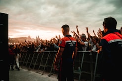 a group of people standing on a bridge with a crowd watching
