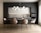 A modern kitchen and dining area with a sleek design. The space features a dark grey cabinet wall, white upper cabinets, and a marble backsplash. A large dining table is surrounded by six beige upholstered chairs with black metal legs. Above the table hangs a contemporary chandelier made of spherical lights. The flooring is a light wood, contributing to a warm and inviting atmosphere.