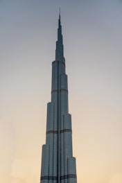 a tall building with a clear sky with Burj Khalifa in the background