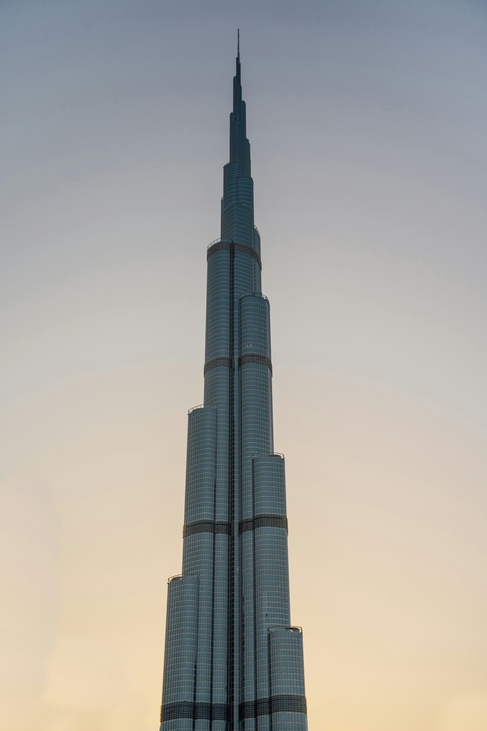 a tall building with a clear sky with Burj Khalifa in the background