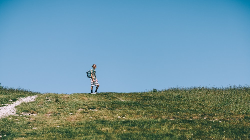 a boy standing on a grassy hill