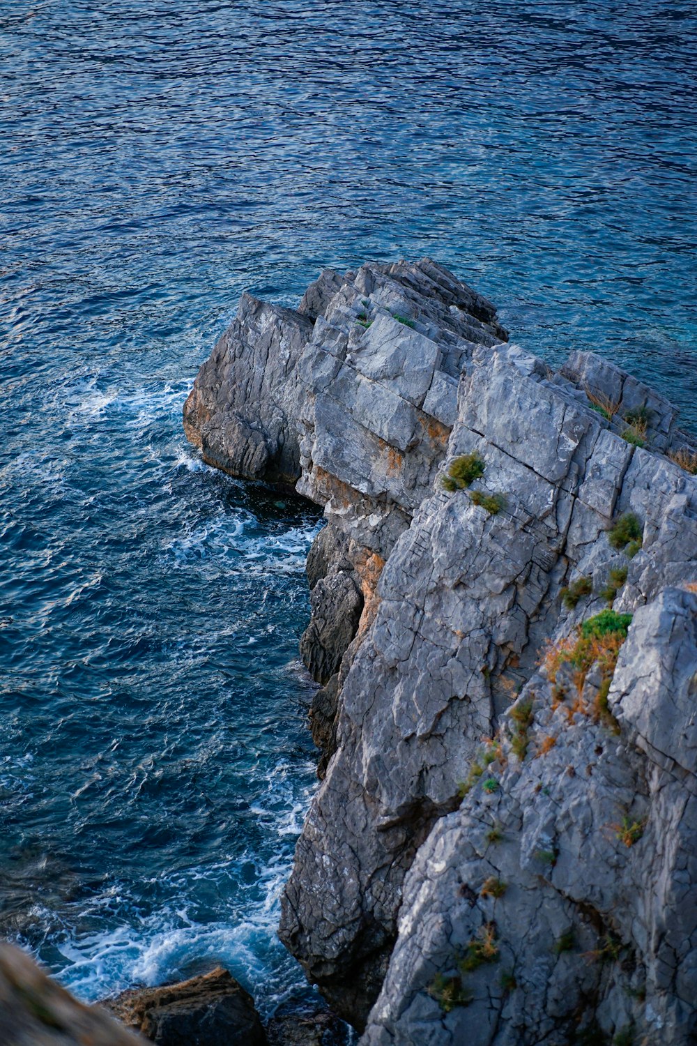 a rock cliff with a body of water in the background