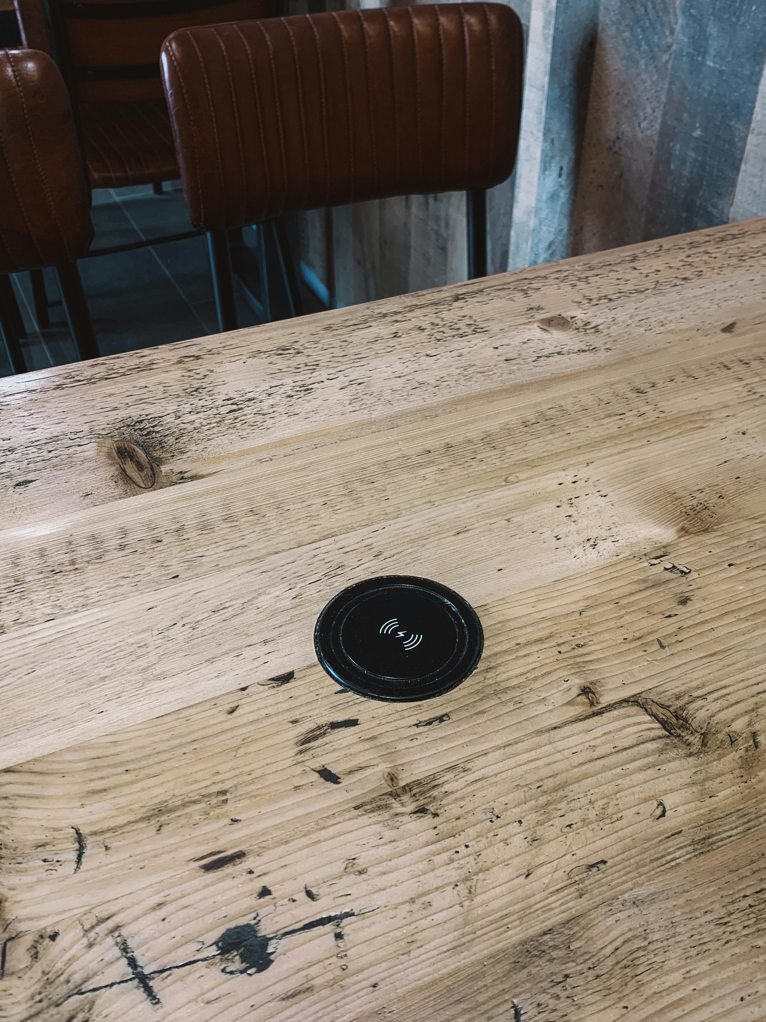 Circular black wireless charging pad on dark wood surface
