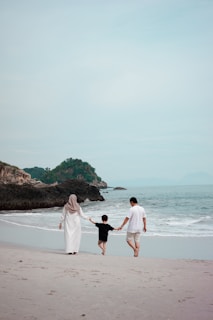 a man and woman and a child walking on a beach
