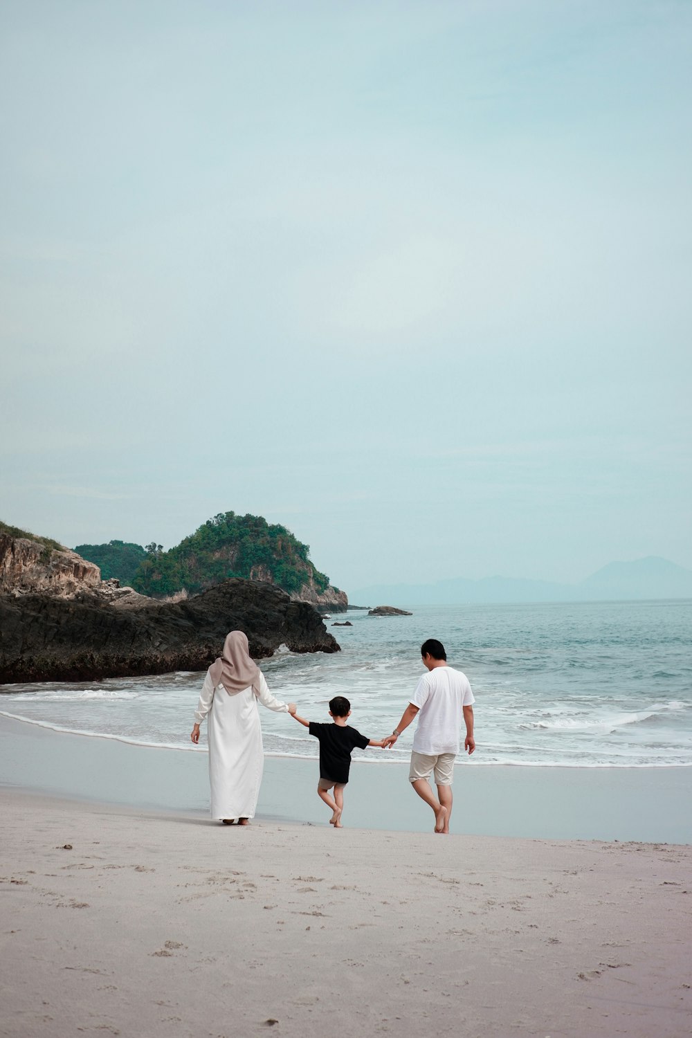 a man and woman and a child walking on a beach