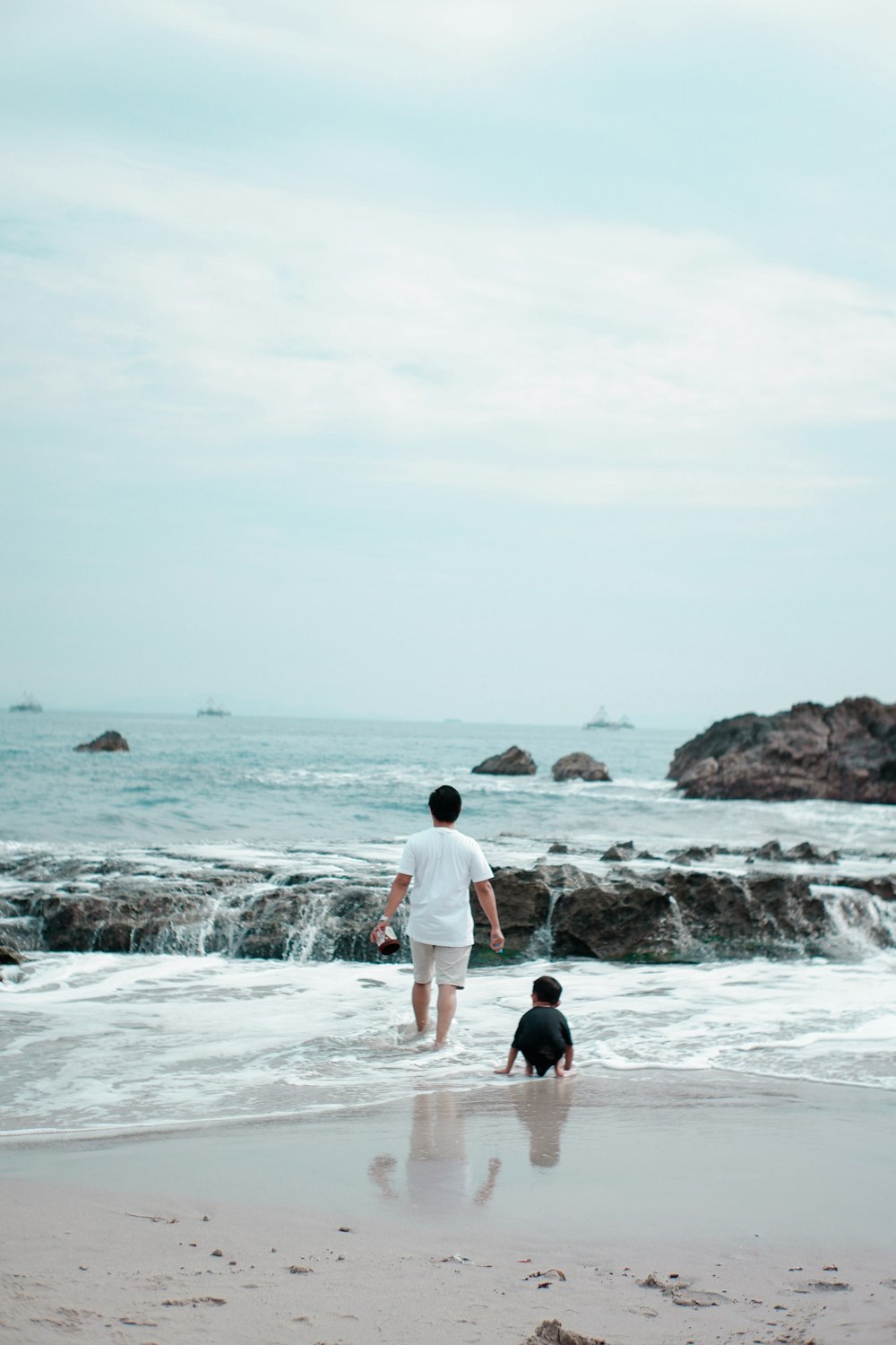 a person and a child walking on a beach