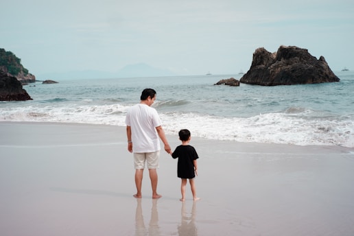 a man and a child walking on a beach