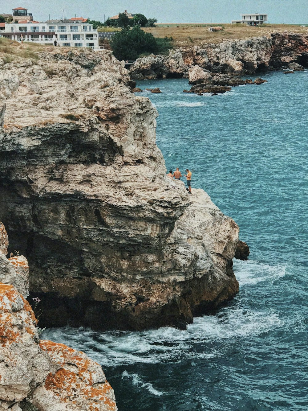 a group of people on a cliff above the ocean