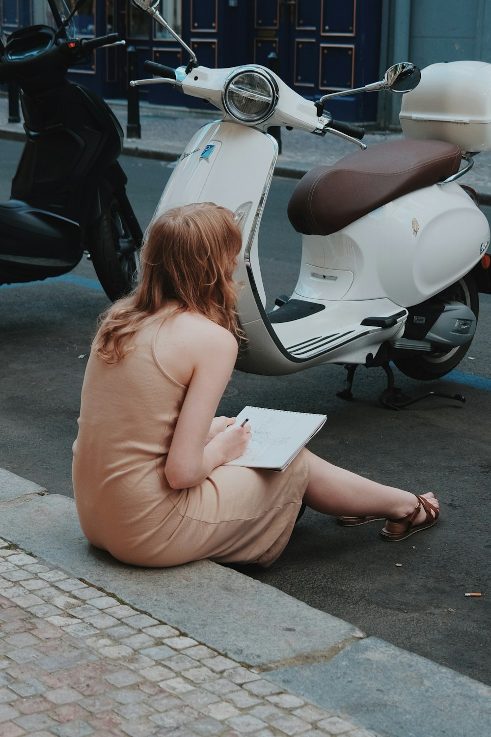 a woman sitting on the sidewalk reading a book