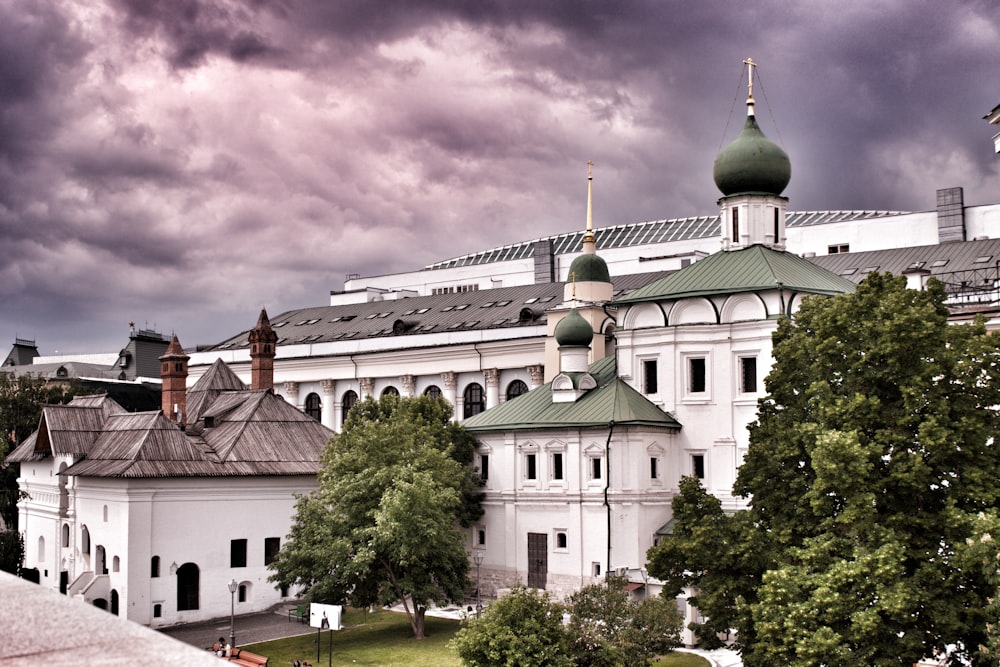 a large white building with a green roof and a green dome