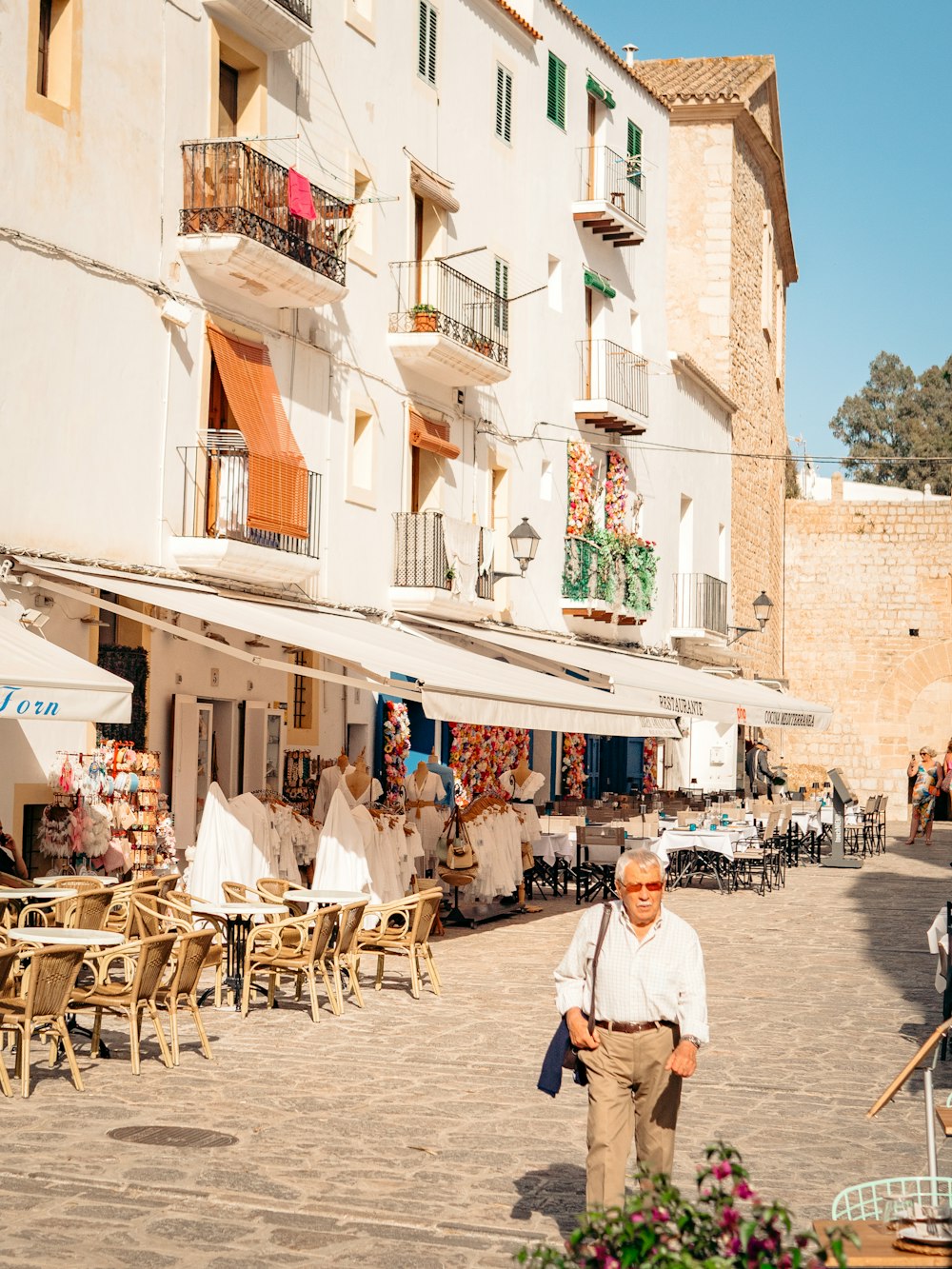 a person standing in front of a building with tables and chairs