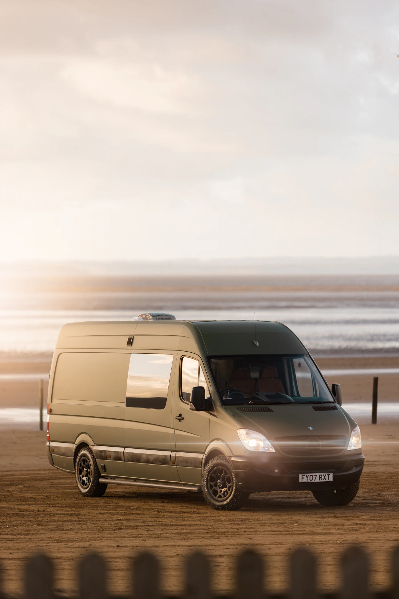 Furgoneta camper aparcada en la playa al atardecer
