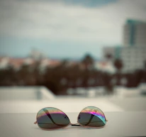 A happy customer trying on sunglasses with a bright cityscape behind.