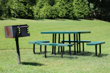 Families enjoying a barbecue under kiosks equipped with churrasqueras and picnic tables