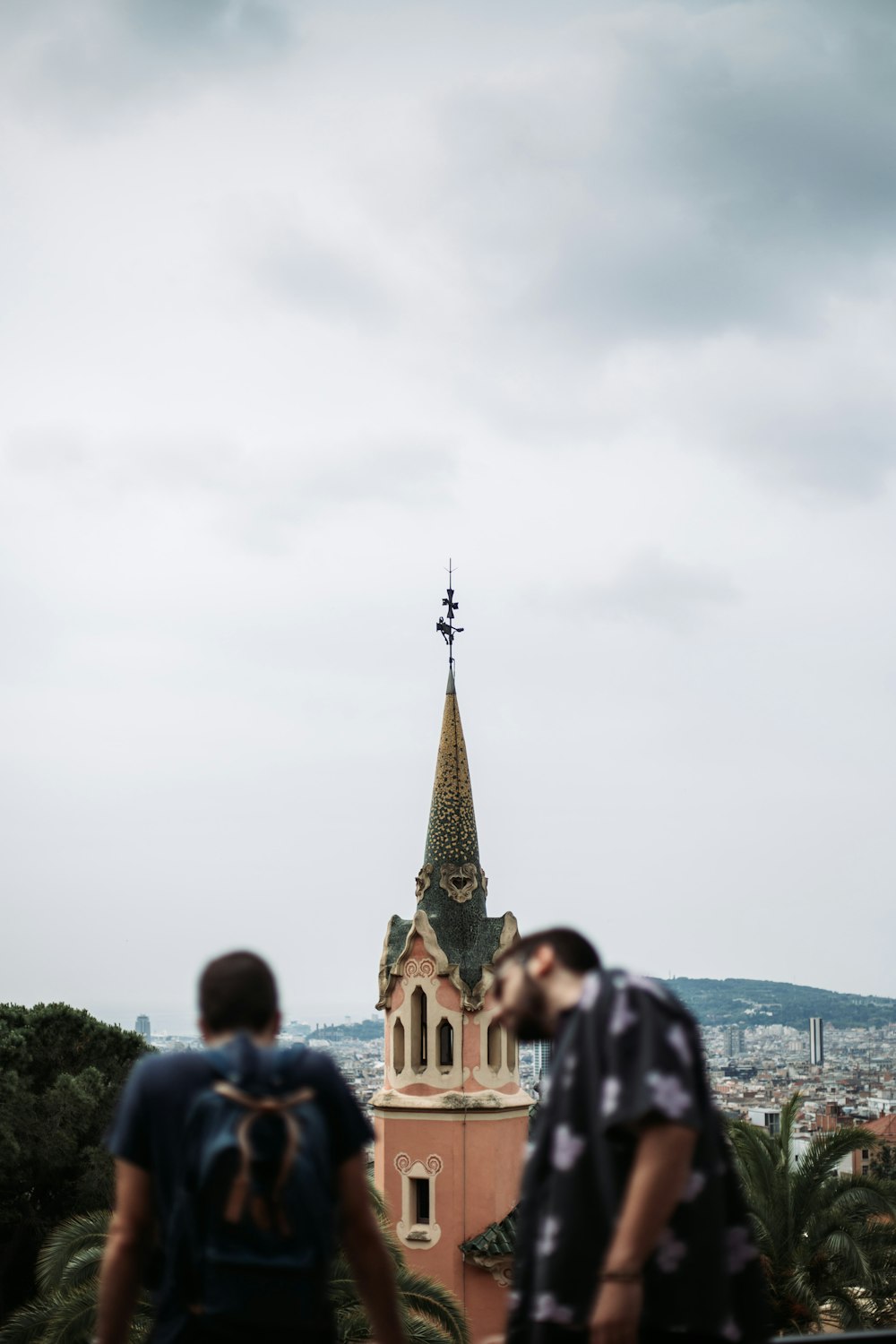 um casal de pessoas se beijando em frente a um prédio alto com uma torre pontiaguda