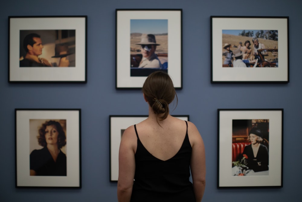 a woman looking at a wall of pictures