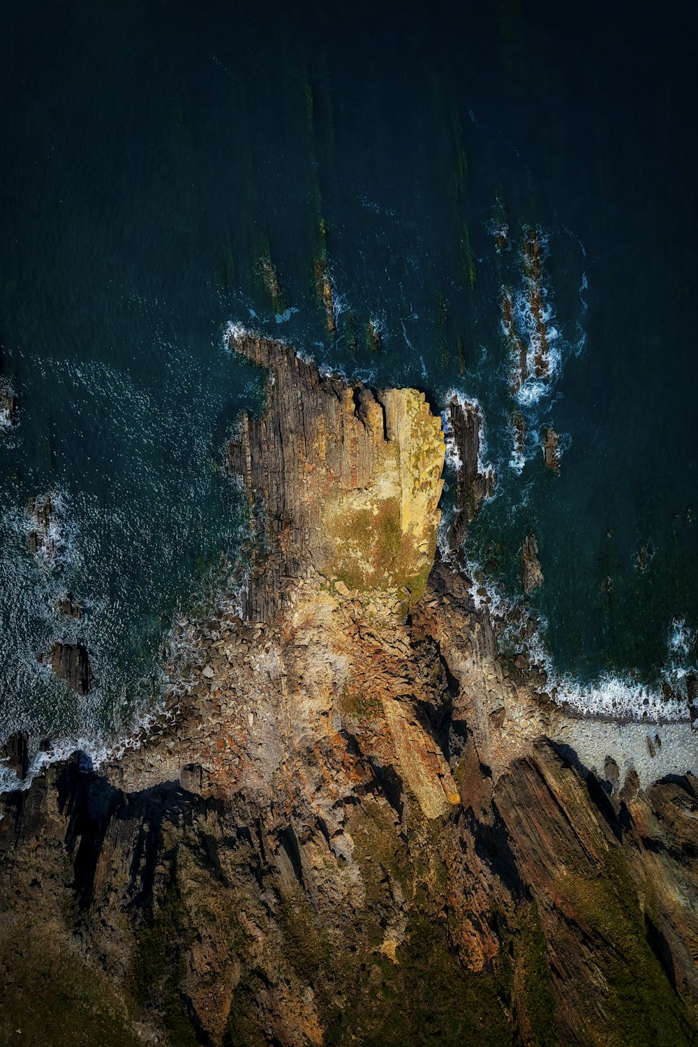 a rocky cliff with a body of water below