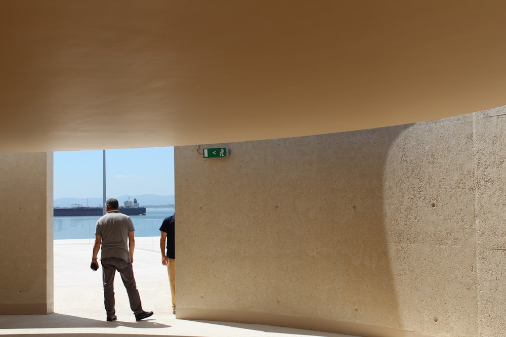 a couple of people looking out a window at the ocean