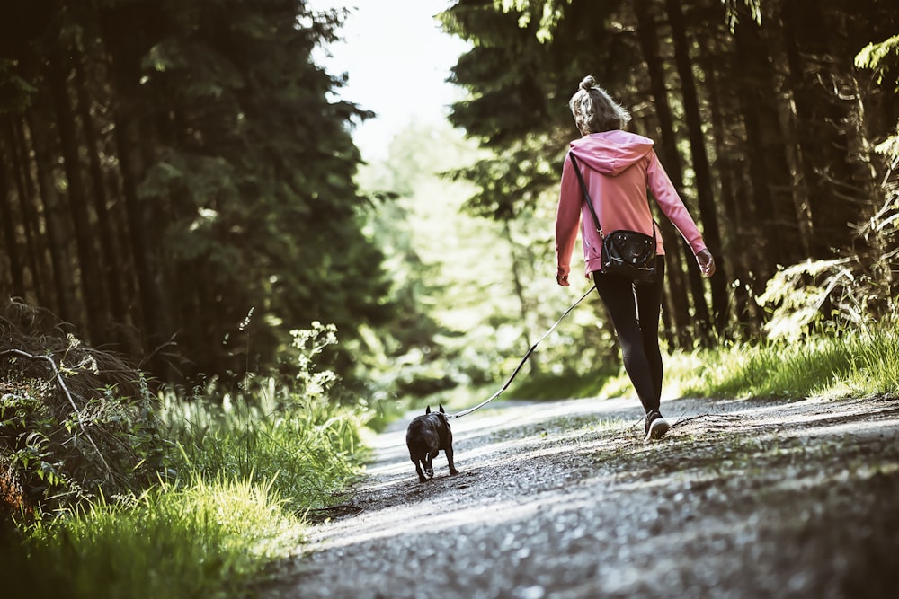 a person walking a dog on a trail in the woods