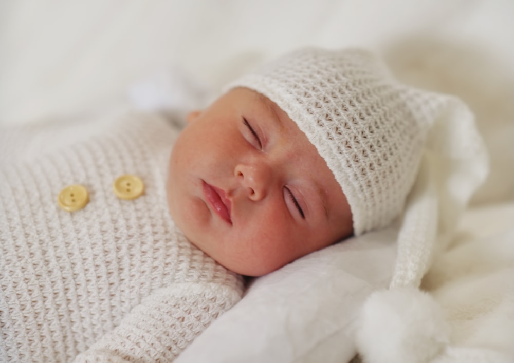 a baby sleeping in a white blanket